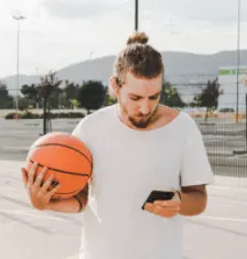 young man holiding basketball and mobile phone